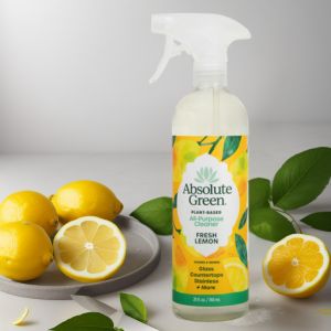 Bottle of Absolute Green Fresh Lemon all-purpose cleaner with fresh lemons and leaves on a neutral background.